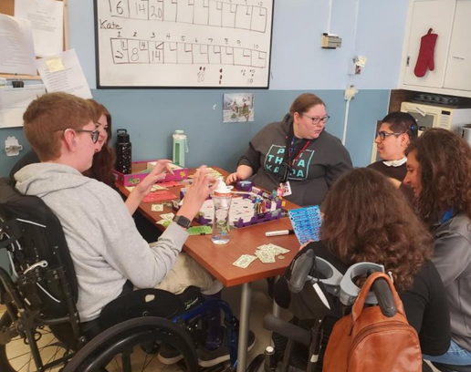 A group of students in their wheelchair sit at a table.