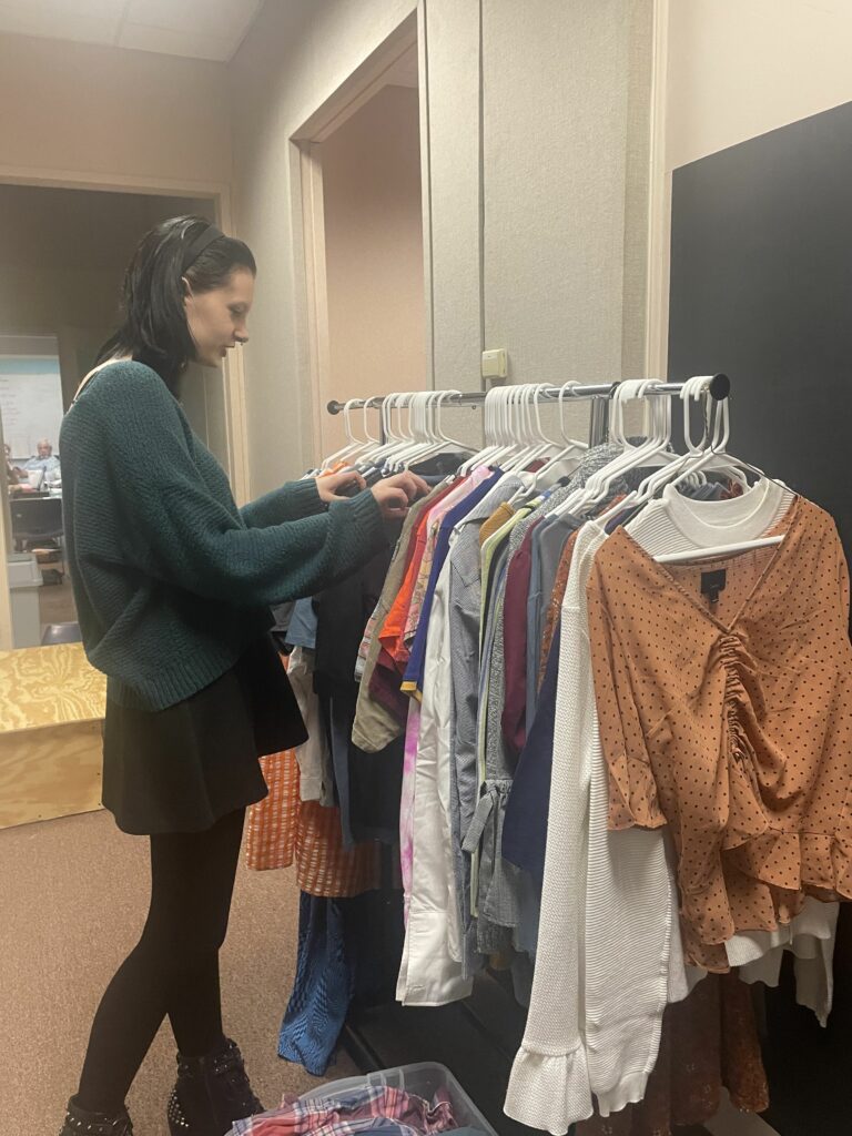 A student looking through clothing racks.
